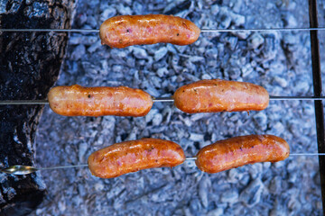 Fried sausages on skewers. Summer evenings near the fire, good weekend. Close-up.