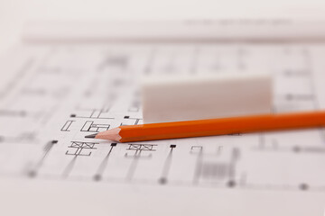 Blueprint with a pencil and eraser on top, representing the concept of design and construction.