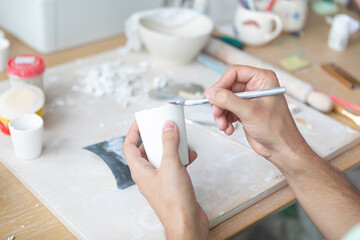 Close-up Image of male hands working with clay mug and making Ceramic Product. Professional Ceramic...