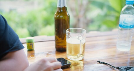 A Asian man is holding a glass of beer drink and laugh with a bottle of beer on background