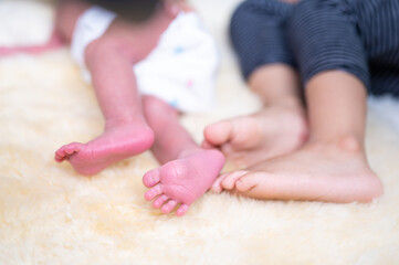 Closeup of newborn baby feet sleeping on bed with older brother
