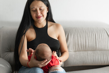 young latina mother carrying her baby on her lap as she settles in for another way to hold her baby.