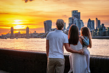 A tourist family on a city trip looks at the skyline of London, England, during a beautiful sunset