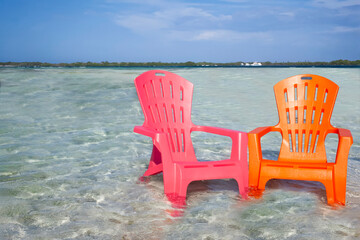 Floating Plastic Chairs on crystal clear turquoise Caribbean Beach in summertime