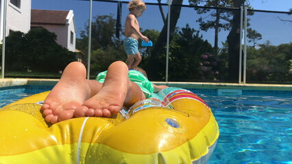 Swimming pool setting, child relaxing on inflatable mattress