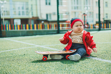 Cute baby sitting on the playground with a skate. Baby on a walk