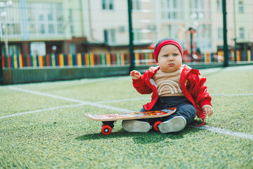 Cute baby sitting on the playground with a skate. Baby on a walk