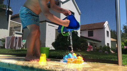 Toddler playing with water and bucket at pool