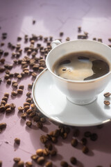 cup of coffee and coffee beans on pink background