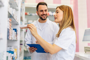 Pharmacists working at the shelfs of pharmacy, drugstore.