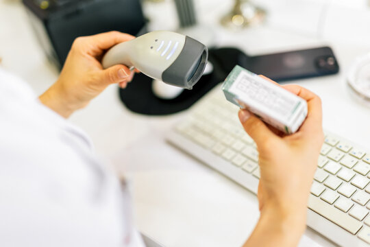 Pharmacist scanning price on a medicine box with barcode reader in pharmacy store.