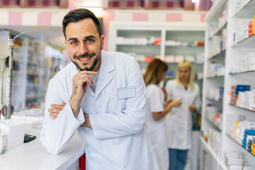 Smiling portrait of young handsome male pharmacist at the pharmacy, drugstore.