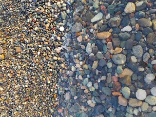 Colorful Sea Pebble stones and rocks underwater on beach. Different forms multicolor Pebbles (green, orange, grey, black) as natural abstract texture background. Close up colorful Pebbles on coast.