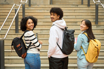 Three multiethnic students looking at camera with their backpacks