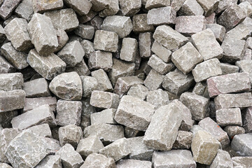 Pile of historic cube shape natural granite cobblestones, background of hammered granite rocks