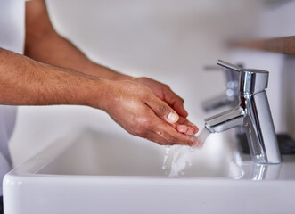 Closeup, water and washing hands in bathroom in home for hygiene, wellness or virus safety in...