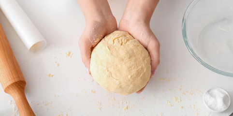 Woman kneading dough for Italian Grissini at white table in kitchen