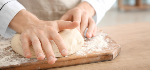Chef kneading dough in kitchen, closeup