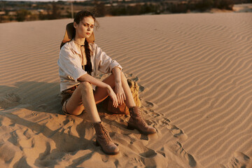 Desolate desert landscape with a woman sitting on top of a sand dune under the scorching sun