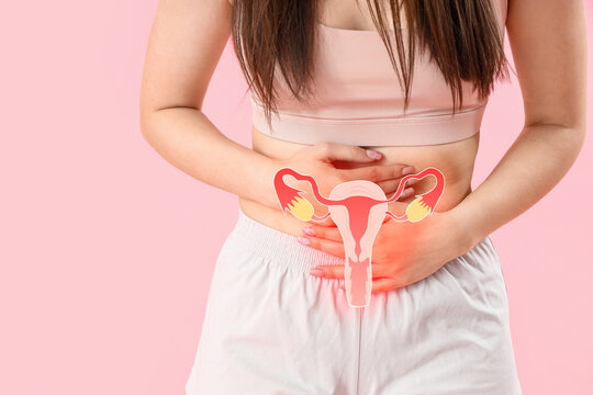 Young woman having menstrual cramps on pink background, closeup