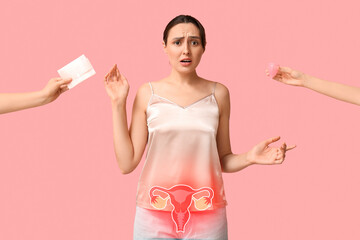 Beautiful worried woman and hands holding menstrual pad with cup on pink background