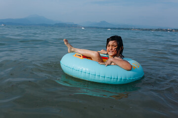 happy girl with short dark hair floating in the water in inflatable ring