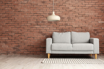 Stylish sofa near brick wall