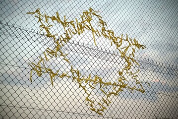 Yellow ribbons tied to a wire fence, in the shape of the Star of David, symbolising the solidarity for hostages taken during the Israel-Gaza War.