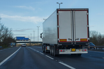 Road transport. White, single no name articulated lorry travelling on the the motorway. View from behind.