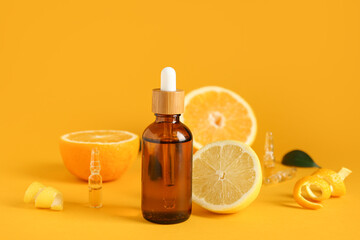 Bottle and ampules of vitamin C with citrus fruits pieces on orange background