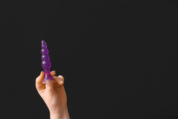 Female hand with anal plug on dark background, closeup
