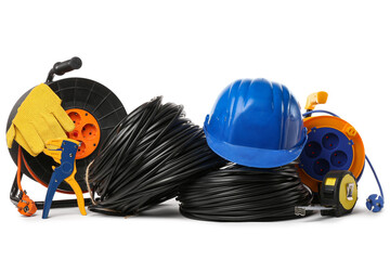 Rolled cables, hardhat, wire stripper and extension cable reels on white background