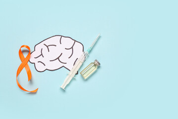 Paper brain with ampule, syringe and orange ribbon on blue background. Multiple Sclerosis Awareness Month