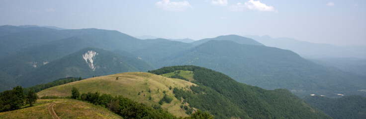 View of the road descending from the top of the mountain. On the horizon are mountains covered with...