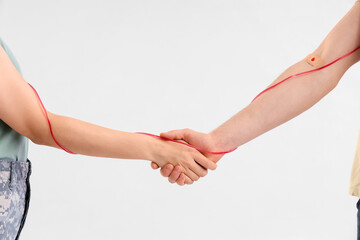 Male blood donor with soldier shaking hands on light background, closeup