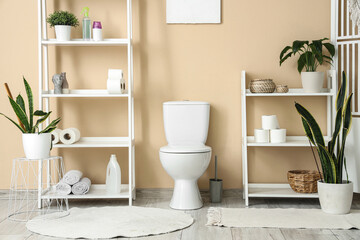 Interior of restroom with toilet bowl near beige wall