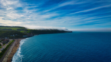 Fototapeta premium Aerial view of coastal landscape with beach and foggy headland in Sandsend, Yorkshire