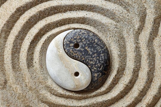 A yin yang symbol created in the sand, showcasing balance and harmony between contrasting forces