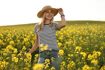 Happy young woman with straw hat in field on spring day