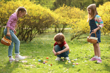 Easter celebration. Cute little children hunting eggs outdoors