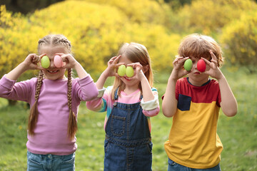 Easter celebration. Little children covering eyes with painted eggs outdoors