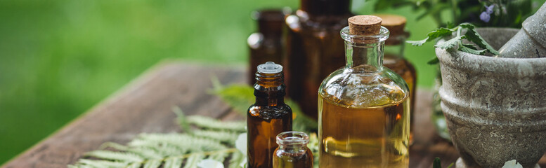 Natural organic essential oil in small glass bottles on wooden background. Homemade production for...