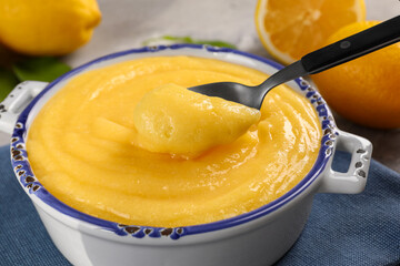 Taking delicious lemon curd from bowl at table, closeup