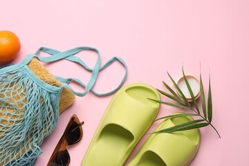 String bag with towel, sunglasses, orange, slippers, cream and palm leaf on pink background, flat...