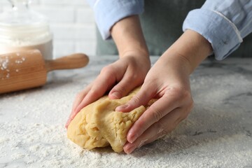 Making shortcrust pastry. Woman kneading raw dough at white marble table, closeup