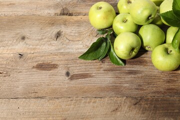Many fresh apples and leaves on wooden table, top view. Space for text