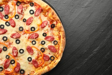 Tasty pizza with cheese, dry smoked sausages, olives and pepper on grey table, top view. Space for text