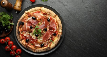 Tasty pizza with cured ham, olives, tomatoes and parsley on black table, top view. Space for text