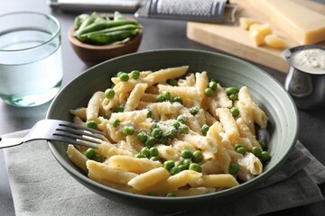 Delicious pasta with green peas served on table, closeup