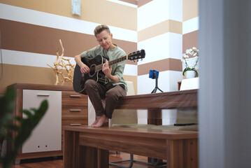 A person learns to play the guitar at home